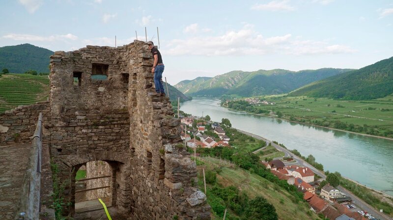 Auf einer Länge von fast 3.000 Kilometern durchquert die Donau zehn europäische Länder, fließt durch lebendige Städte und winzige Dörfer. An ihren Ufern erstrecken sich unberührte Auen und Kulturlandschaften. Am Fluss wurde und wird Geschichte geschrieben. Aber hier wird auch gefeiert, getrauert und gelebt. – Für die Sonnwendfeier in der Wachau werden Fackeln in Ruinen aufgestellt. – Bild: rbb/Michael Donnerhak Auf einer Länge von fast 3.000 Kilometern durchquert die Donau zehn europäische Länder, fließt durch lebendige Städte und winzige Dörfer. An ihren Ufern erstrecken sich unberührte Auen und Kulturlandschaften. Am Fluss wurde und wird Geschichte geschrieben. Aber hier wird auch gefeiert, getrauert und gelebt. – Für die Sonnwendfeier in der Wachau werden Fackeln in Ruinen aufgestellt. – Bild: rbb/Michael Donnerhak