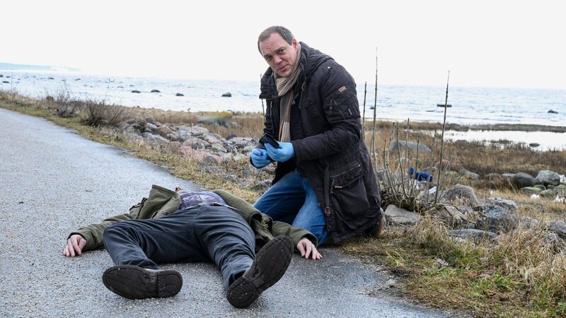Thomas (Andy Gätjen) untersucht den Toten (Ville Norberg): wurde dieser erschossen, als in sein Haus eingebrochen wurde? – Bild: SRF/​ZDF/​Marion von der Mehden