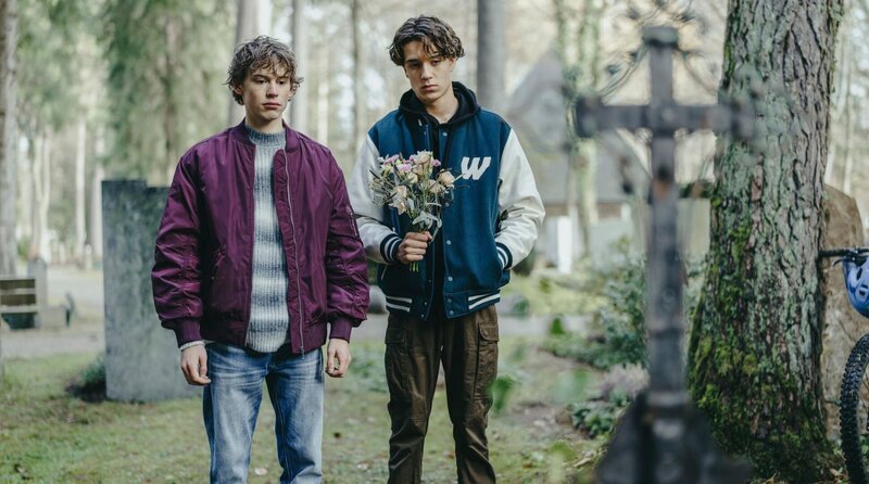 Jan (Philip Günsch, li.) und Lukas (Marven Suarez Brinkert) am Grab von Jans Mutter. Sie reden über Jans Familie. – Bild: ARD Degeto Film/​Bantry Bay Productions GmbH/​Hendrik Heiden