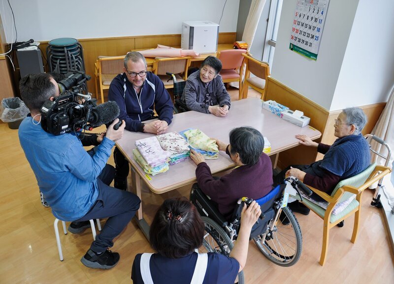 Dreharbeiten im Alterspflegeheim im Spital von Onagawa. Die Stadt wurde 2011 vom Tsunami zerstört und das Spital mit Schweizer Hilfe wieder aufgebaut. Patrick Rohr unterhält sich mit Bewohnerinnen. – Bild: ZDF und SRF/​Reto Vetterli