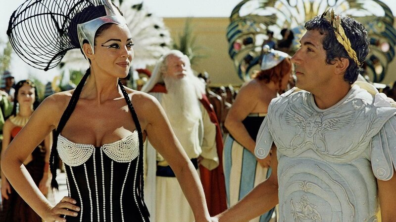 Kleopatra (Monica Bellucci) hat sich auf eine Wette mit Cäsar (Alain Chabat) eingelassen. Sie wettet mit ihm, dass es die Ägypter schaffen, innerhalb von drei Monaten einen Palast zu bauen. – Bild: RTL Deutschland