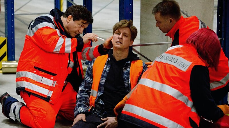 ARD FAMILIE DR. KLEIST VIII. STAFFEL FOLGE 101, „Das große Zittern“. Christian (Francis Fulton-Smith, l.) ist als Notarzt vor Ort: Boris Kehr (Jürgen Klein, M.) wurde von einer herabfallenden Pallette verletzt (mit Komparsen, r.). – Bild: ARD/​Volker Roloff