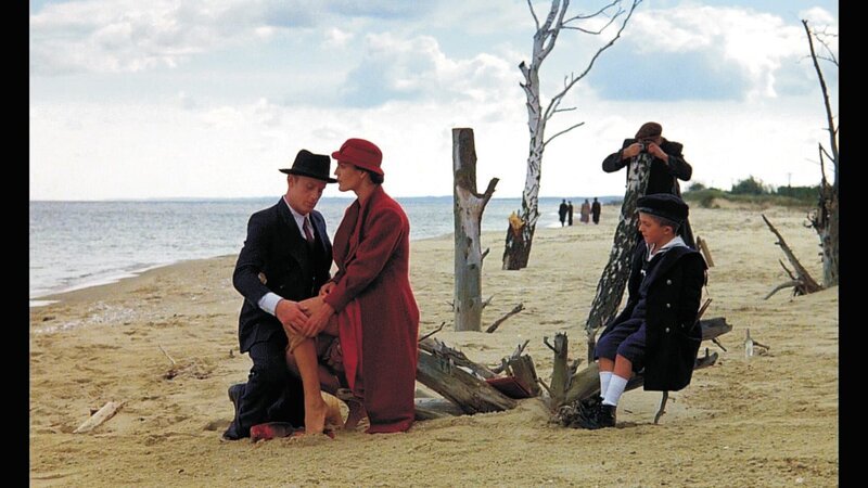 Bei einem Ausflug an die See wird Oskar (David Bennent, re.) Zeuge der heimlichen Zärtlichkeiten zwischen seiner Mutter Agnes Matzerath (Angela Winkler) und ihrem Vetter Jan Bronski (Daniel Olbrychski). Sein Vater Alfred Matzerath (Mario Adorf, im Hintergrund) scheint noch ahnungslos. – Bild: TVP Bei einem Ausflug an die See wird Oskar (David Bennent, re.) Zeuge der heimlichen Zärtlichkeiten zwischen seiner Mutter Agnes Matzerath (Angela Winkler) und ihrem Vetter Jan Bronski (Daniel Olbrychski). Sein Vater Alfred Matzerath (Mario Adorf, im Hintergrund) scheint noch ahnungslos. – Bild: TVP