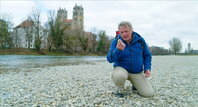 Jeder Stein erzählt eine Geschichte. Colin Devey schaut sich die Kiesel am Münchner Flaucher genauer an. Sie stammen nicht nur aus den Kalkalpen des Tiroler Karwendel, wo die Isar entspringt, sondern teilweise auch aus sehr weit entfernten Gegenden. – Bild: ZDF und Ricardo Esteban Garzon Mesa