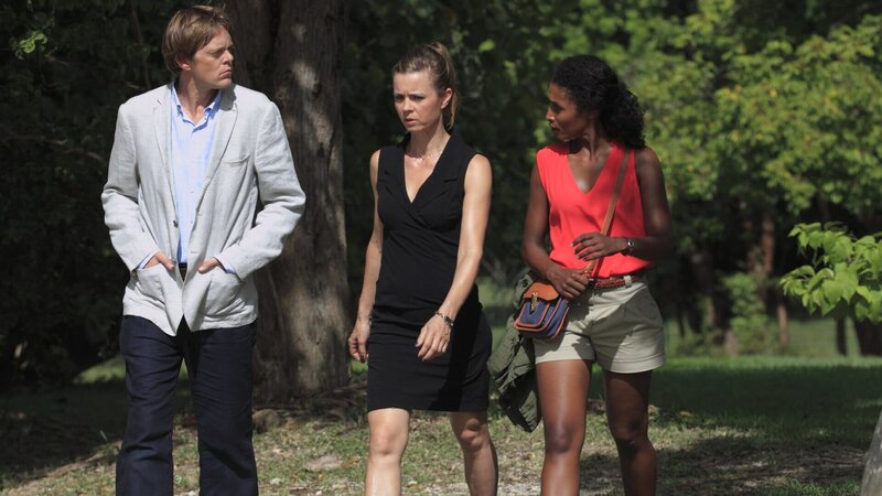 Auf seinem Anwesen auf Sebastien Island wird Alexander Jackson ermordet. Humphrey (Kris Marshall, l.) und Camille (Sara Martins, r.) befragen Emily (Caroline Proust, M.), eine der zu der Tatzeit Anwesenden. – Bild: ZDF und Denis Guyenon
