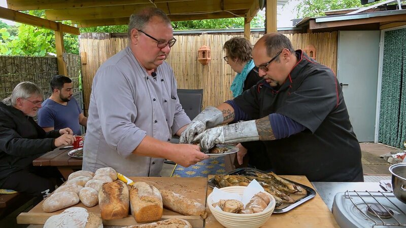 Kleingartenchef Alex (re.) verwöhnt seine Gäste mit geräucherten Forellen – inklusive Holzofenbrot.; Kleingartenchef Alex (re.) verwöhnt seine Gäste mit geräucherten Forellen – inklusive Holzofenbrot. – Bild: RTLZWEI