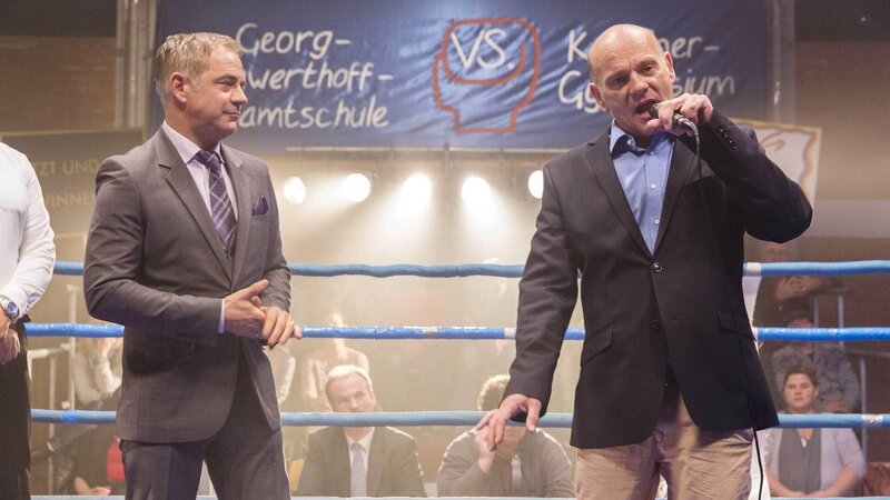 Die Direktoren Schwengers (Florian Fitz, l.) und Rose (Ulrich Gebauer) begrüßen die Zuschauer zum Boxkampf. – Bild: TVNOW /​ Frank Dicks