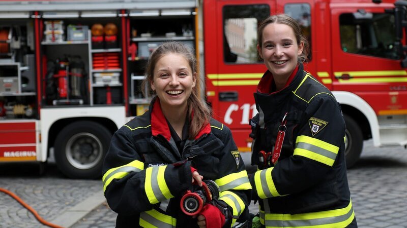 Mit Feuerwehrfrau Lisi checkt Marina (links) wie die Arbeit bei der Feuerwehr ist und darf sogar auf einen richtigen Einsatz mitfahren! – Bild: BR/​megaherz gmbh/​Robin Worms