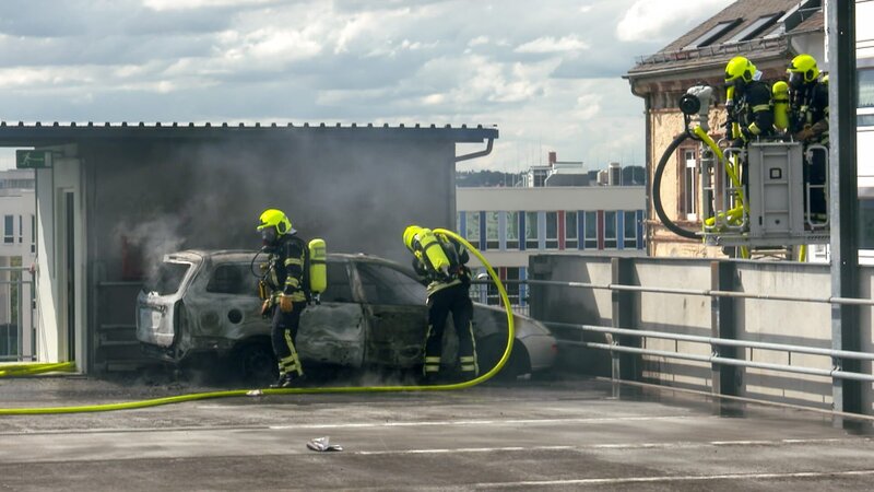 Feuerwehrleute löschen ein brennendes Auto. – Bild: Warner Bros. Discovery, Inc. or its subsidiaries and affiliates.