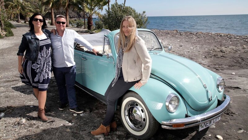 Episode 002 – Ann Jenkins (L), Christopher Jenkins (C) and Brigitte Fernandez (R) standing next to a blue car on a beach, with the Mediterranean sea behind them, in the area of La Herradura – Bild: Scripps Networks, LLC