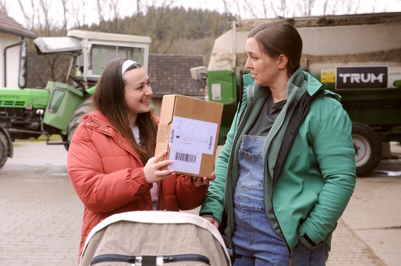 Maja (Godiva Adela, rechts) zeigt Sophia (Patricia Freund) stolz, das Paket mit ihrem neuen Nagellack. – Bild: BR /​ Marco Orlando Pichler