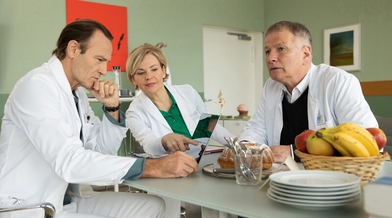 Dr. Martin Stein (Bernhard Bettermann, li.) bespricht seinen Patientenfall mit seinen Freunden und Kollegen Dr. Kathrin Globisch (Andrea Kathrin Loewig, mi.) und Dr. Roland Heilmann (Thomas Rühmann, re.). – Bild: MDR/​Saxonia Media/​Rudolf Wernicke