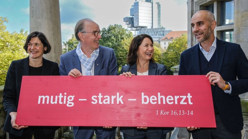Die Organisatoren und Organisatorinnen: Generalsekretärin Kristin Jahn (l.), Landesbischof Ralf Meister (2.v.l.), Präsidentin Anja Siegesmund (2.v.r.) und Oberbürgermeister Belit Onay (r.) werben mit der Losung für den 39. Evangelischen Kirchentag in Hannover. – Bild: ZDF und Jens Schulze Die Organisatoren und Organisatorinnen: Generalsekretärin Kristin Jahn (l.), Landesbischof Ralf Meister (2.v.l.), Präsidentin Anja Siegesmund (2.v.r.) und Oberbürgermeister Belit Onay (r.) werben mit der Losung für den 39. Evangelischen Kirchentag in Hannover. – Bild: ZDF und Jens Schulze