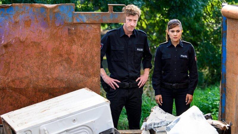 Henk Cassens (Maxim Mehmet) und Süher Özlügül (Sophie Dal) sind bestürzt als sie sehen, wer da tot im Container liegt. – Bild: ZDF und Willi Weber