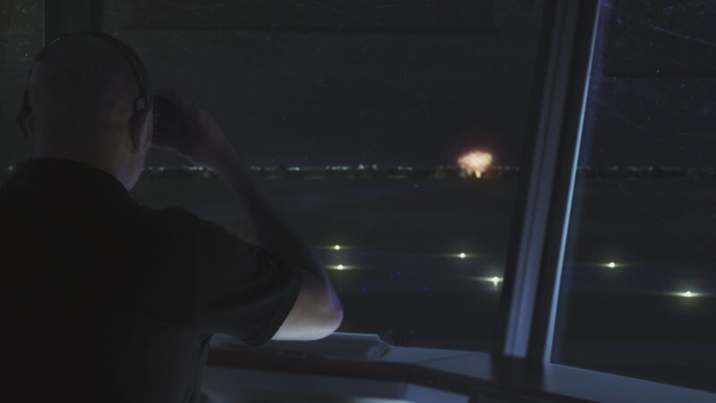 REENACTMENT – The Air Traffic Controller (played by Jamie Robinson) looks out of the window with binoculars at the explosion from the crash of Comair Flight 5191. – Bild: James Griffith /​ Cineflix