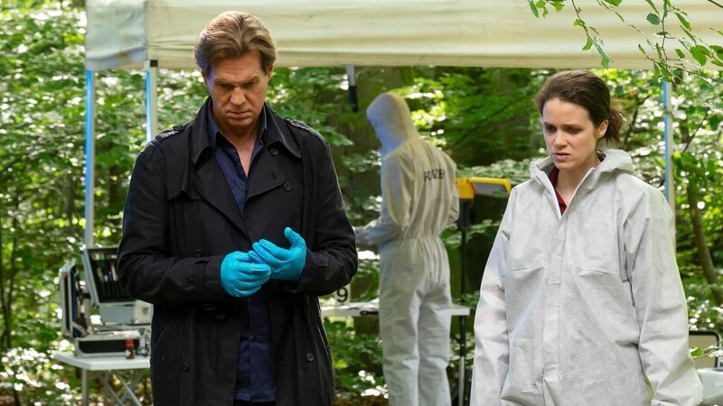 Am Tatort im Wald starren ratlose Ermittler auf den Boden: Thomas Heinze als Caspar Bergmann, Sidonie von Krosigk als Dr. Luisa Geiger – Bild: SRF/​ZDF/​Erika Hauri