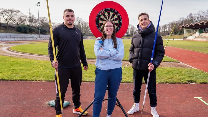 Speerwerfer Max Dehning (l.) und Dartspielerin Julia Siek (M.) stellen sich der Challenge von Moderator Eric Mayer (r.): Sie tauschen ihre Sportgeräte. Können sie ihre jeweiligen Ziele erreichen? – Bild: ZDF und Florian Lippke