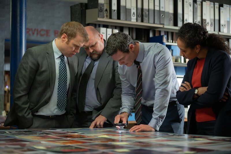 Das Team von DCS Steve Wilkins (Luke Evans, 2.v.r.) sucht in alten Fotos nach neuen Beweisen. Neben Wilkins stehen DS Glyn Johnson (Richard Corgan (2.v.l.), DS Gareth Rees (Charles Dale, l.) und DI Ella Richards (Alexandria Riley). – Bild: ZDF und Warren Orchard