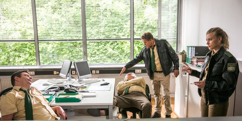 Riedl (Paul Sedlmeir, l.) und Girwidz (Michael Brandner, 2.v.l.) haben über Nacht im Revier Schnaps gebrannt und sind dabei eingeschlafen. – Bild: ARD/​TMG/​Chris Hirschhäuser