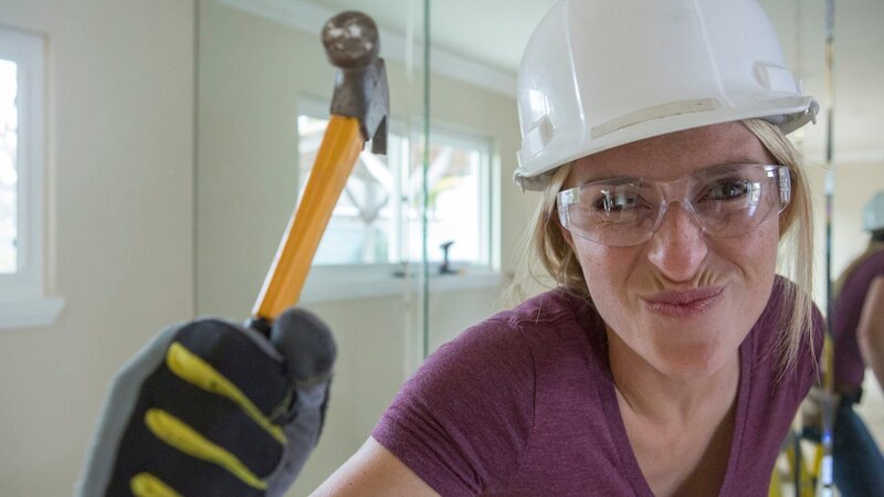 As seen on Hidden Potential, designer Jasmine Roth playfully holds a small hammer before removing a large living room wall mirror during demo at the Yapelli residence in Huntington Beach, CA. – Bild: HGTV. All Rights Reserved./​Gilles Mingasson/​Getty Images
