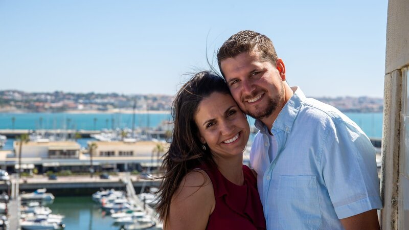Sandra Miller (L) and Dwight Miller (R) standing on a viewing terrace with marina in Cascais, Portugal in the background, smiling to the camera and being happy about their new life in Portugal, as seen on Mediterranean Life (portrait) – Bild: Scripps Networks, LLC
