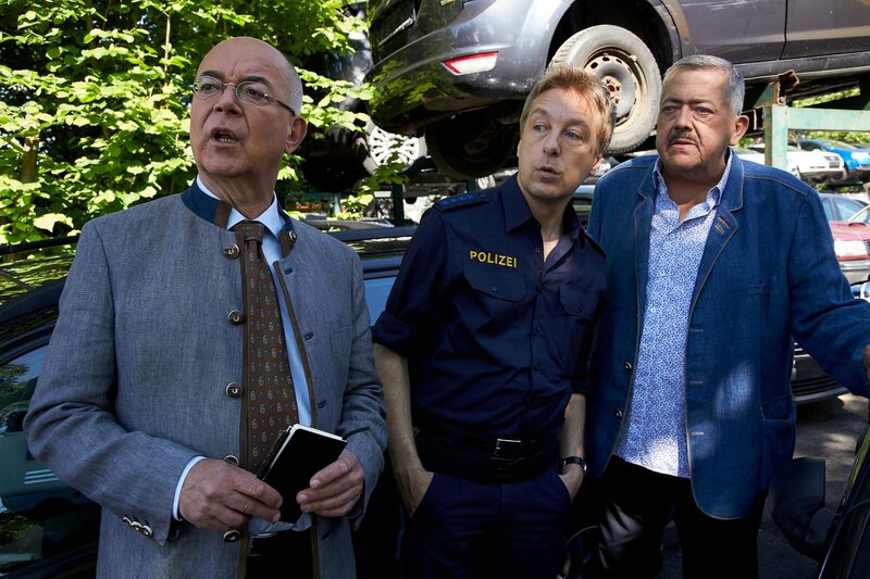 Polizeidirektor Achtziger (Alexander Duda, l.), Kommissar Hofer (Joseph Hannesschläger, r.) und Polizeihauptmeister Mohr (Max Müller, M.) entdecken eine Überwachungskamera auf dem Autoschrottplatz. Ob die Bilder der Kamera zur Aufklärung des Falls beitragen können? – Bild: Bojan Ritan /​ ZDF Enterprises GmbH /​ Die Verwendung ist nur bei redaktioneller Berichterstattung im Rahmen einer Programmankündigung ab 2 Monate vor der ersten Auss /​ © ZDF/​Bojan Ritan