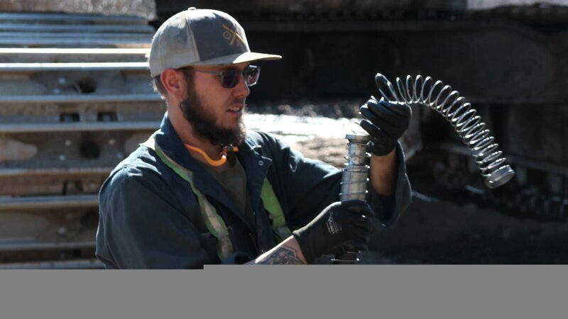 Kevin Beets with spring whilst fixing excavator – Bild: Warner Bros. Discovery, Inc. or its subsidiaries and affiliates.