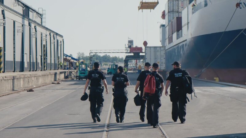 Polnische Grenzschutzbeamte auf dem Weg zur Kontrolle eines Containerschiffs aus Südamerika im Hafen von Gdansk. – Bild: Warner Bros. Discovery