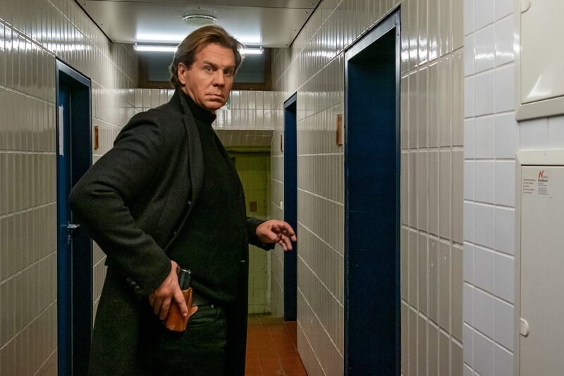 Caspar Bergmann (Thomas Heinze) ist auf der Hut, als er alleine die Mannschaftsräume betritt. – Bild: Erika Hauri /​ ZDF