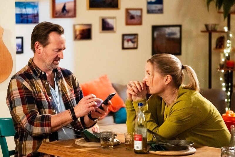 Gregor (Holger Matthias Wilhelm) und Vera (Sybille Waury) haben einen Streit, da Vera denkt, die Nachrichten der Sprachlernapp „Elena“ stammen von einer Frau. – Bild: Lena Semmelroggen /​ BR