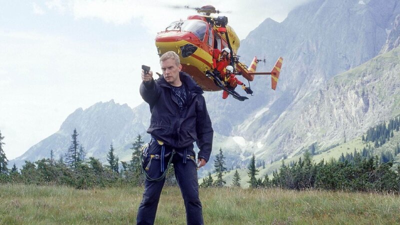 Gerade noch von den dienstfreien Kollegen des Medicopter-Teams gerettet, zieht der kriminelle Rick (Sebastian Bezzel) plötzlich die Pistole und droht, den Hubschrauber abzuschießen, falls nicht getan wird, was er verlangt. Der Crew bleibt nichts anderes übrig, als darauf einzugehen … – Bild: RTL /​ Miguel Dieterich