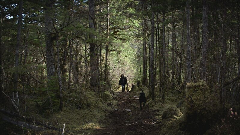 PORT PROTECTION, ALASKA- Timbi geht mit ihrem Hund Smokey durch den Wald. (Bildnachweis: National Geographic Channels/​Jesse Phinney) – Bild: Copyright © The National Geographic Channel.