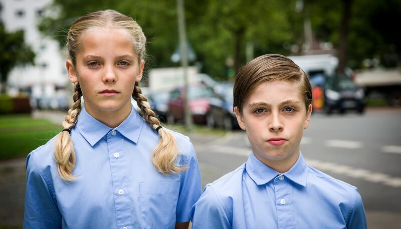 Als brave „Nationale Demokraten“ verkleidet, interviewen Stella (Zoë Malia Moon, li.) und Till (Otto von Grevenmoor, re.) die Nachbarn der Asylbewerberfamilie Kelmendi. – Bild: NDR/​Boris Laewen