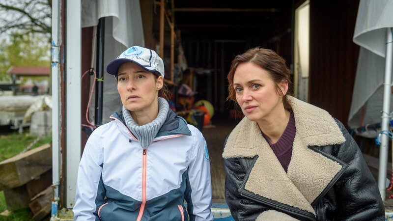 Der Verein „Frei Atmen“ hat mit dem örtlichen Segelverein kooperiert. Doch im Gespräch mit der Vorsitzenden Miriam Kunze (Lisa Marie Janke, l.) erfährt Karoline Joost (Nike Fuhrmann, r.), dass die Zusammenarbeit mit dem Opfer nicht immer einfach gewesen ist. Es hat sogar richtig Ärger im Segelclub gegeben. Sind die beiden Frauen etwa in Streit geraten? Ist dieser eskaliert? – Bild: ZDF und ZDF /​ Meyerbroeker