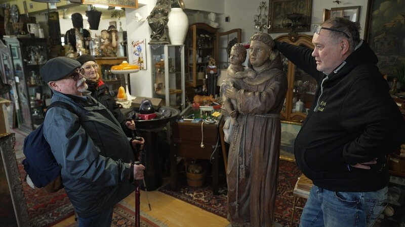 Waldi unterhält sich mit zwei Pilger in seinem Laden. – Bild: ZDF und Warner Bros. Deutschland