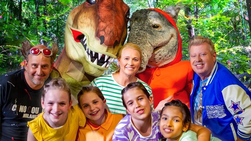 Beim Ausflug in den Dinopark treffen die TanzAlarm-Kids, Tom Lehel, Singa, TanzTapir und Kindermusiker Volker Rosin auf einen neuen Freund. – Bild: KiKA/​MingaMedia/​Ron Bergmann