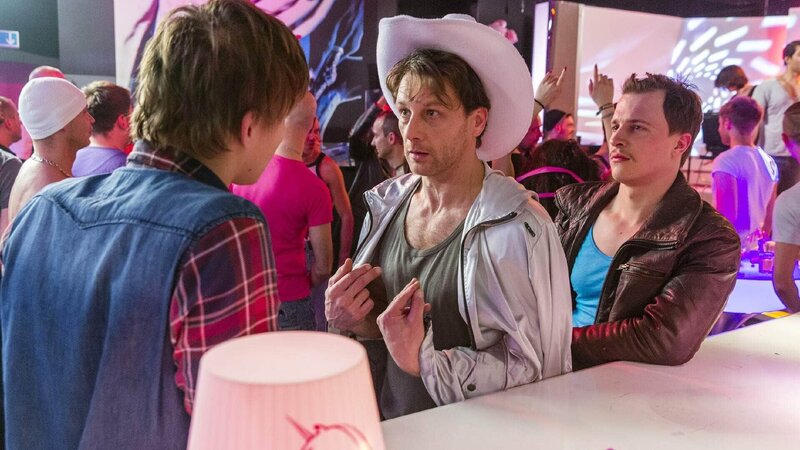 Stefan (Hendrik Duryn, M.) versucht Jonas (Merlin Rose, l.) und Ben (Tim Kalkhof) im Karaoke-Club Uganda auszureden. – Bild: TVNOW /​ Frank Dicks