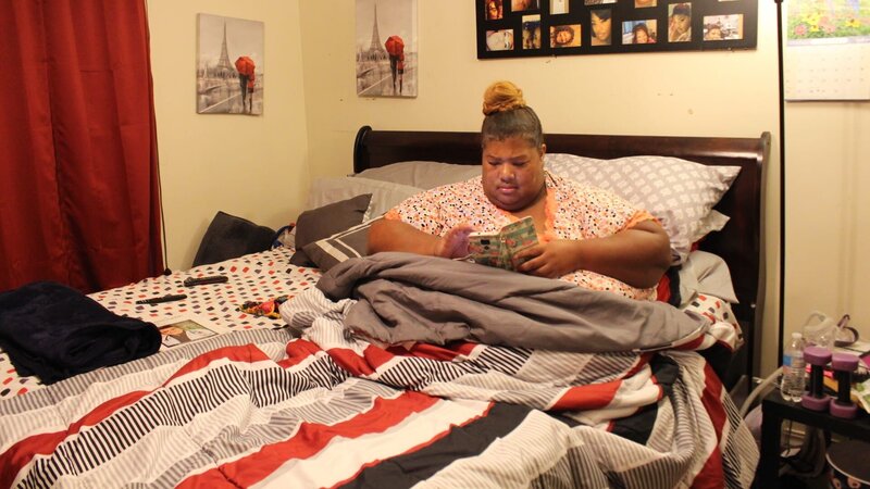 Latonya in bed reading. – Bild: Warner Bros. Discovery, Inc. or its subsidiaries and affiliates. All rights reserved.