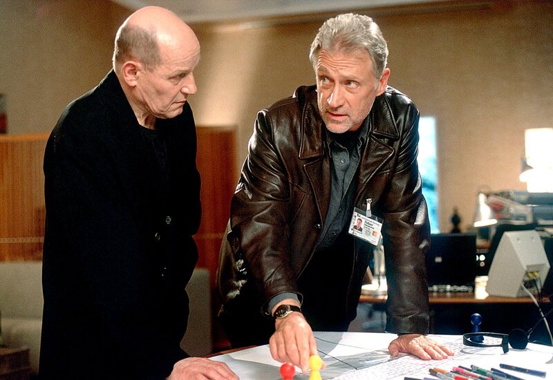 Jan Casstorff (Robert Atzorn, rechts), der sich in die Verhandlungen eingeschaltet hat, weil sich sein Sohn Daniel an Bord der entführten Maschine befindet, erläutert seinem neuen Chef Bruno Kern sein weiteres Vorgehen. – Bild: NDR/​Thorsten Jander