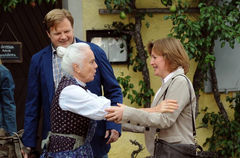 Theresa gibt Max und Vroni die letzten Glückwünsche mit auf den Weg. Von links: Theresa (Ursula Erber), Max (Michael Grimm) und Veronika Brunner (Senta Auth). – Bild: BR/​Marco Orlando Pichler