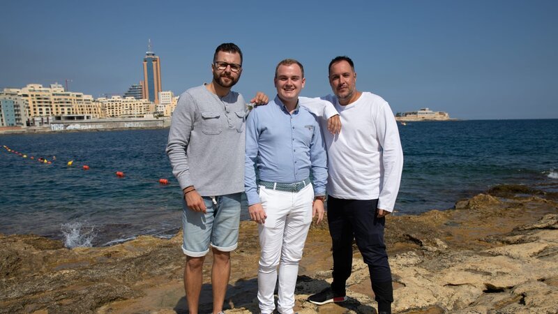 Adam Thomison (R) with his friend Milos Sarac (L) and Colin Porter Johnson (C), the realtor, standing at the waterfront in the area of Sliema, Malta, as seen on Mediterranean Life – Bild: Scripps Networks, LLC.