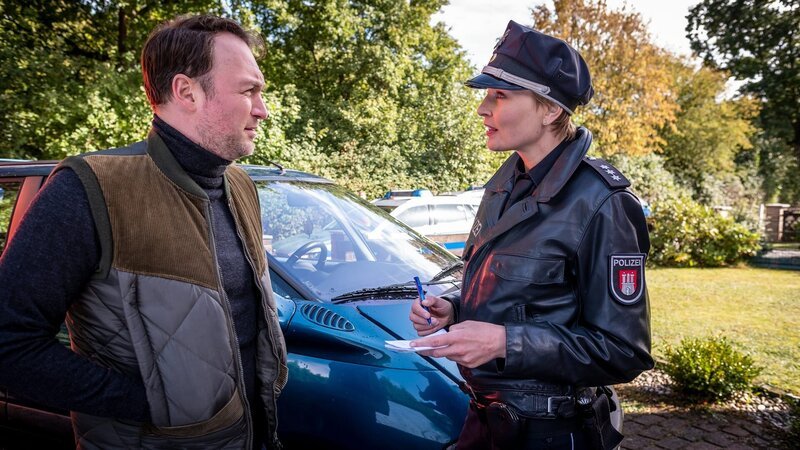 Melanie (Sanna Englund) spricht mit Thies Scholtens (Martin Stange), dem Nachbarn der Hertels, der Justin Hertels gefunden hat, nachdem er angeblich in seinem Haus überfallen wurde. – Bild: ZDF und Boris Lasewen