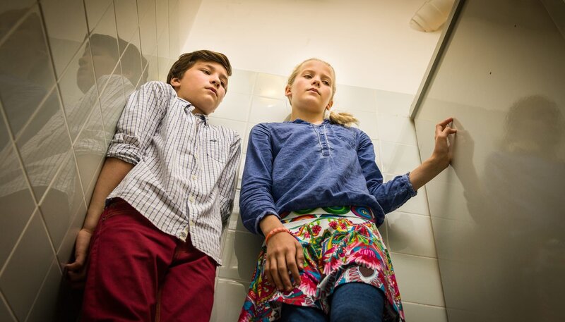 Ramin (Jann Piet, li.) und Stella (Zoë Malia Moon, re.) müssen sich auf der Damentoilette des Krankenhauses verstecken … – Bild: NDR/​Boris Laewen