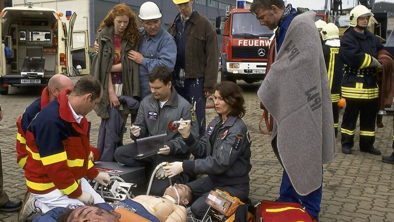 Thomas (Ulrich Bähnk, 3.v.r.) und Ilona (Julia Heinemann, 2.v.r.) kämpfen um das Leben der Verletzten, die bei einer schweren Verpuffung auf der Reparaturwerft verunglückt sind. – Bild: ZDF und Boris Laewen