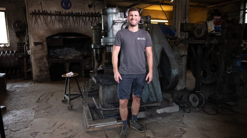 Bei Pfannenproduzent Stefan Kindermann entstehen unter den gewaltigen Schlägen einer Hammerschmiede Eisenpfannen samt Stiel aus einem Stück, die als besonders robust und unempfindlich gelten. – Bild: Vera Blume /​ BR, Constantin Entertainment GmbH