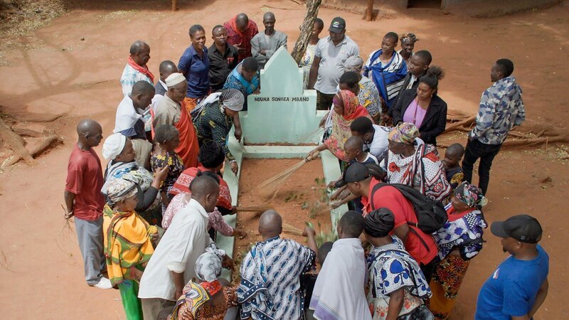 Die Protagonisten John Mbano, Aidan Mbano und ihre Familie gedenken dem ermordeten Songea Mbano an dessen Grab. – Bild: ZDF und Marcus Winterbauer