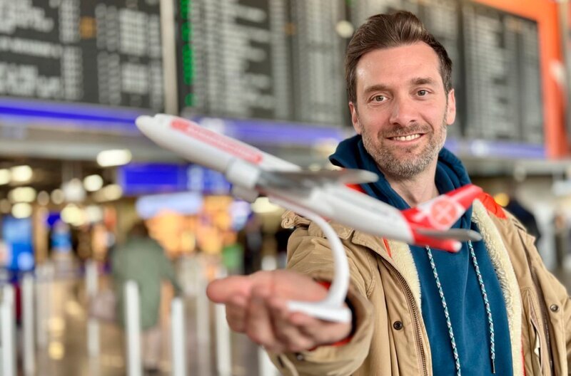 Last Minute oder doch früh buchen? Daniel Aßmann checkt bei „Ausgerechnet – Fliegen“ einige Tipps und Tricks und erfährt auf Deutschlands größtem Flughafen was sein Kurztrip von Frankfurt nach Wien eigentlich kostet. – Bild: WDR/​Bavaria Entertainment GmbH/​Paul Bogdanski