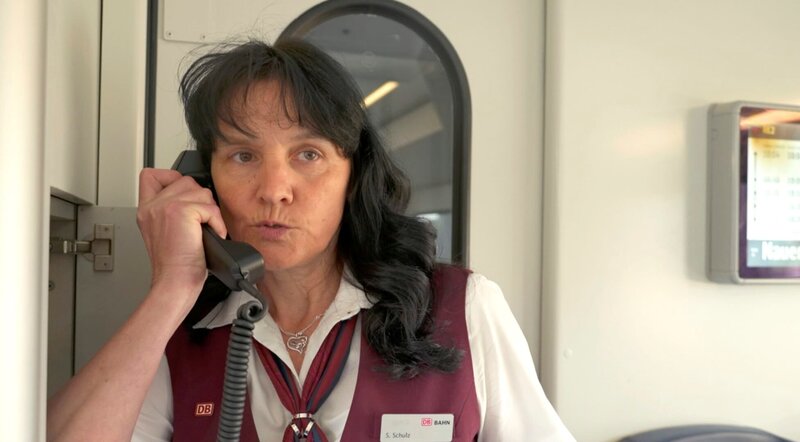 Der Regionalexpress 2 ist eine der beliebtesten Zugverbindungen der Region: Stündlich fährt er von Cottbus über Berlin bis nach Nauen und wieder zurück. Die Fahrt ist eine Reise voller Gegensätze durch Stadt und Land, durch eine Region im Wandel mit Blick auch auf ihre Bewohner – Alteingesessen und Zugezogene. – Die Kundenbetreuerin Sandra Schulz im RE 2. – Bild: rbb/​Guido Kilbert