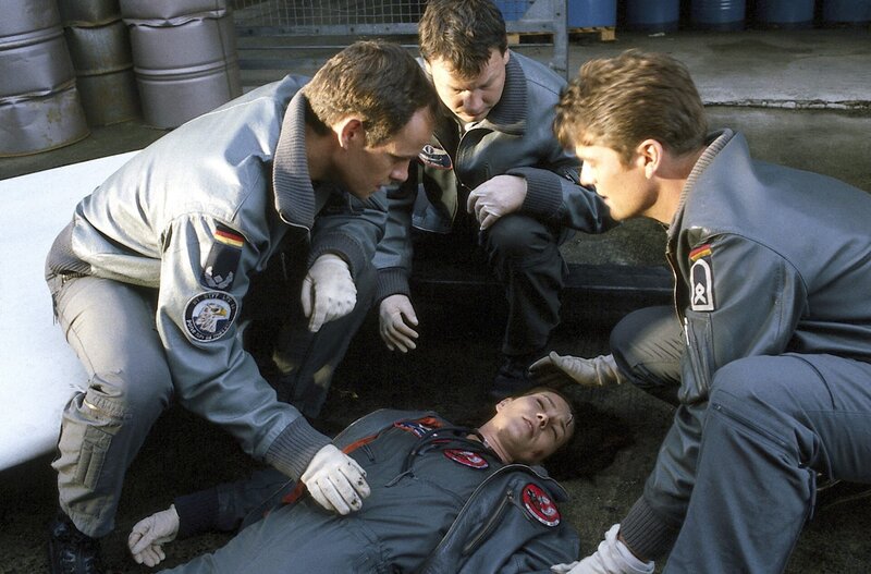 Alex (Matthias Leja, l.), Thomas (Ulrich Bähnk, M.) und Wollcke (Oliver Hörner, r.) wollen „ihre“ Ärztin Ilona (Julia Heinemann, liegend) selbst ins Krankenhaus fliegen. – Bild: ZDF und Boris Laewen