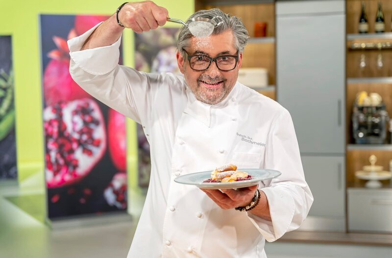 Starkoch Hans Jörg Bachmeier hält einen Löffel und ein Tellergericht in der Hand.; Starkoch Hans Jörg Bachmeier bestäubt einen Teller mit Pfannkuchen. – Bild: BR/​Ralf Wilschewski